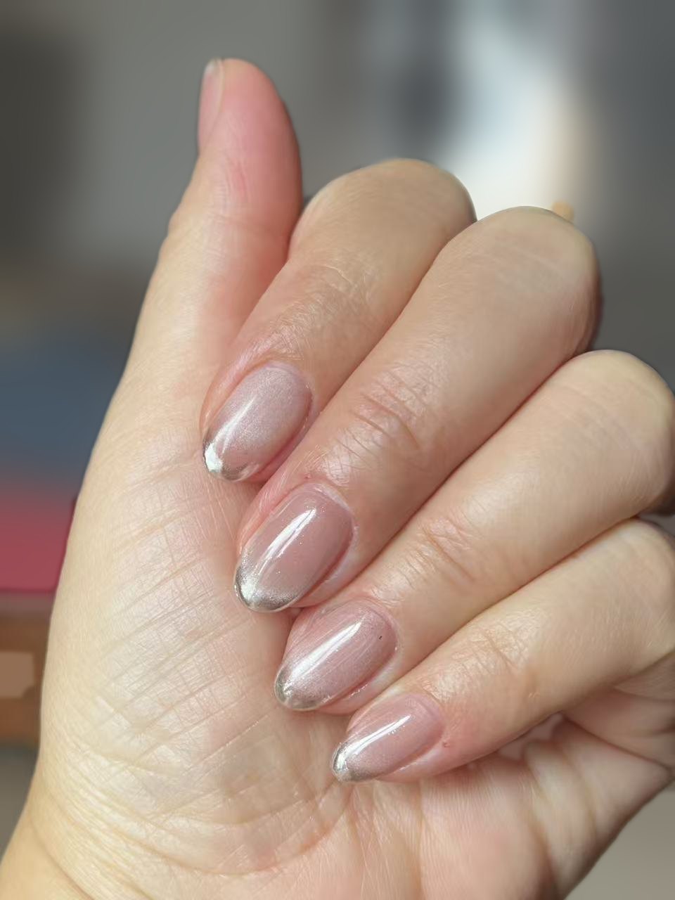 Short oval nails in sheer nude with soft silver chrome tips